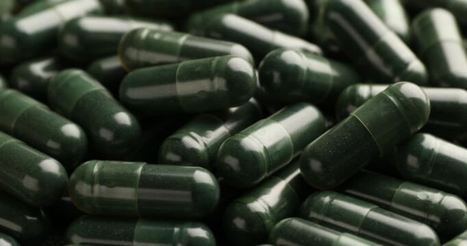 Pile of spirulina capsules, spinning. closeup view