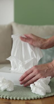 Woman taking paper tissue out of box at wooden table indoors, closeup