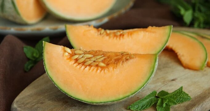 Woman putting piece of Cantaloupe melon on wooden table, closeup