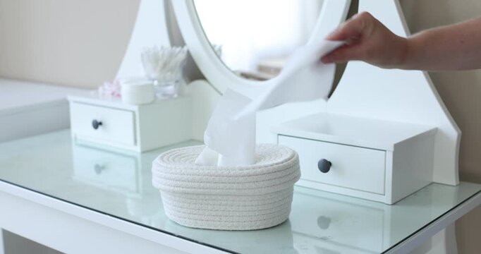 Woman taking paper tissue out of basket at dressing table indoors, closeup
