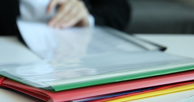 Businesswoman taking file folder at table, closeup