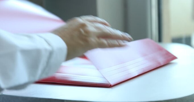 Businesswoman placing punched pocket with paper sheet into file folder at table, closeup