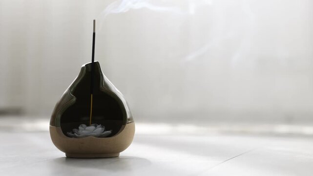 Smoldering incense stick on floor indoors, closeup