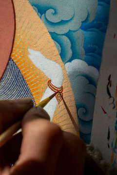 Tibetan artist painting clouds and ornaments on a thangka at a workshop, Qinghai Province, Wutun, China