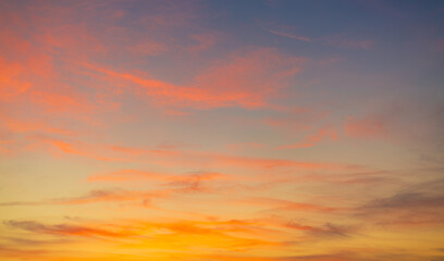 Fototapeta premium Vibrant Sunset Sky Panorama with Colorful Orange Pink and Blue Clouds,A panoramic photograph capturing a vibrant sunset sky filled with wispy cirrus clouds illuminated in golden yellow, orange, pink, 
