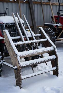 Winter agriculture and farm maintenance, snow covered vintage wooden hay rake and tractor equipment in cold weather during the winter season