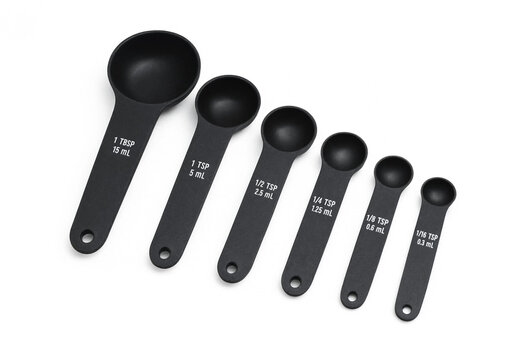 Set of black plastic measuring spoons of various sizes with kitchen utensil