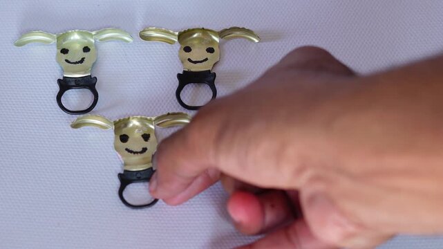 Hand arranging upcycled bottle cap craft on a white background