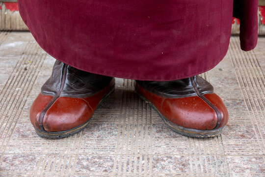 Close-up of traditional leather boots beneath a monk's robe at Hezuo monastery, Gansu Province, Hezuo, China