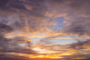 Fototapeta premium Vibrant Sunset Sky Panorama with Colorful Orange Pink and Blue Clouds,A panoramic photograph capturing a vibrant sunset sky filled with wispy cirrus clouds illuminated in golden yellow, orange, pink, 