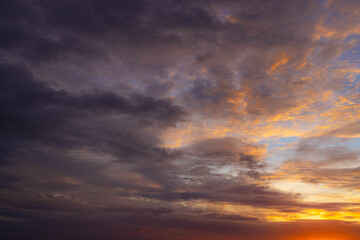 Fototapeta premium Vibrant Sunset Sky Panorama with Colorful Orange Pink and Blue Clouds,A panoramic photograph capturing a vibrant sunset sky filled with wispy cirrus clouds illuminated in golden yellow, orange, pink, 