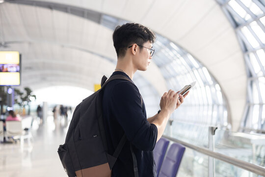 close up young asian man smile and looking while holding passport ,ticket and smartphone in airport departure area for traveling and people lifestyle concept