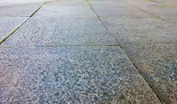 Angle view of gray square stone paving slabs with rough textured surface, outdoor stone floor tiles