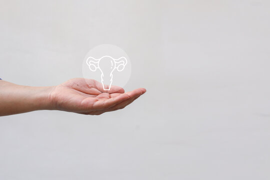 woman hand show uterus symbol on beige background represent about health checkup and lifestyle for health and wellness concept