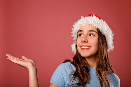Smiling girl in santa hat presenting copy space