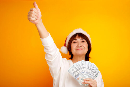 Woman in santa hat holding money and giving thumbs up