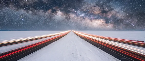 Strait highway across snow-covered salt flat with light trails under Milky Way galaxy © suman