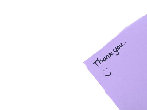 Close up of a purple torn paper corner with handwritten thank you text and a cute happy face on white background with copy space, ideal for gratitude design, marketing, and appreciation cards