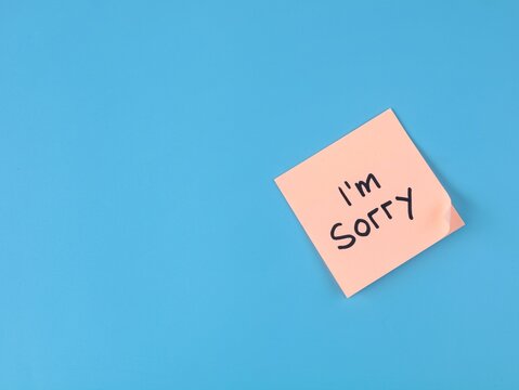 Peach adhesive note with handwritten I'm sorry text placed on blue background with copy space. Ideal for apology concepts, regret, relationship reconciliation, and emotional communication designs