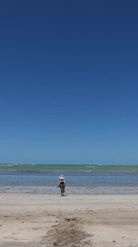 Pessoa caminhando sozinha em praia deserta com mar ao fundo, cena de solid&atilde;o contemplativa e liberdade durante viagem tranquila ao litoral