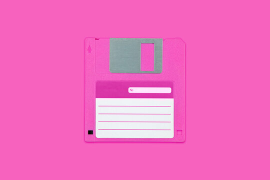 Pink vintage floppy disk with white sticker label isolated on matching pink back