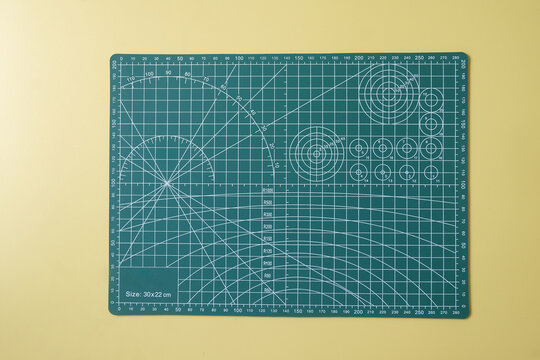 A green colored cutting mat tool with ruler and angles.