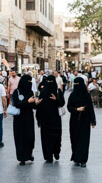 Three women in niqab walking in traditional market