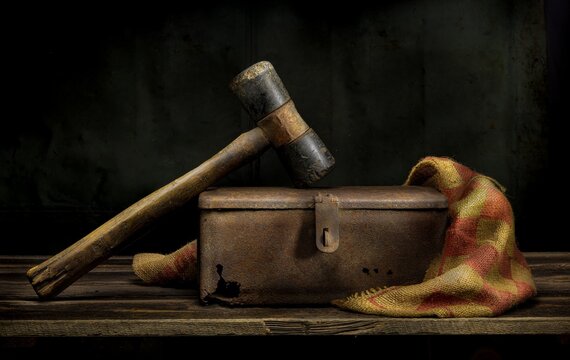 Old hammer resting on rusted metal box in vintage still life.