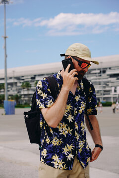 Man in Floral Shirt Talking on a Phone Outdoors