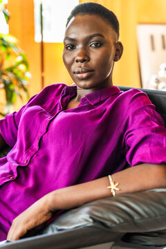 Model Sits in Chair Wearing Purple Shirt Indoors at a Studio