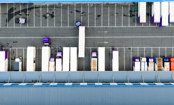 Aerial top view of logistics warehouse with solar rooftops and trucks