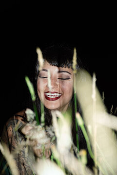 Woman Smiling in a Dark Field With Plants at Night