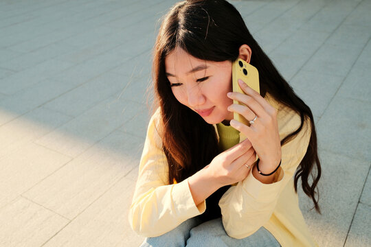 Young relaxed stylish asian woman talking on the phone in the street