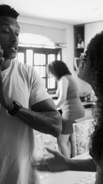 African American father raising hands in frustration while arguing with teenage children