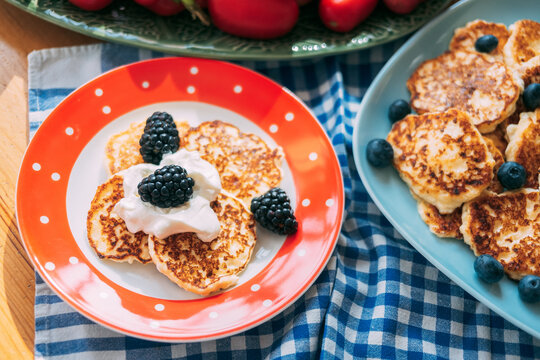 Pancakes with berries and cream served on colorful plates