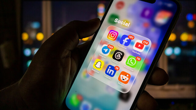 Close up view of hand holding smartphone with social media apps on screen.
