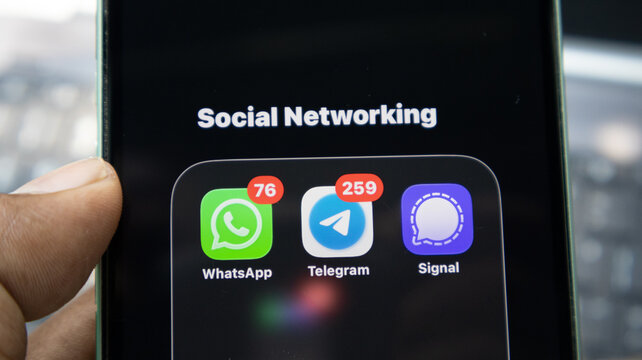 Smartphone screen displaying social networking folder with WhatsApp Telegram and Signal messaging app icons and notification badges.