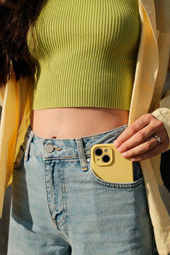 Close up crop of anonymous woman holding mobile phone in the pocket