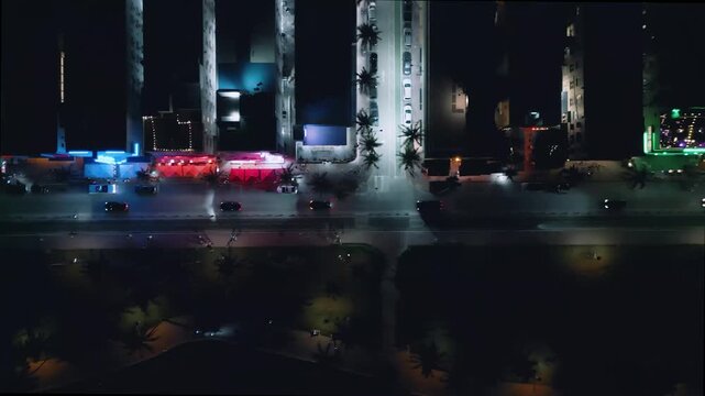 Vibrant neon reflections flood Collins Avenue in this dynamic Miami Beach aerial night sequence
