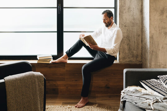 Person reading book relaxing at home by window