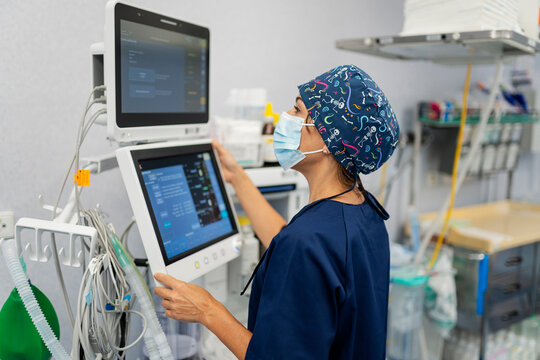 Anesthesiologist adjusting medical ventilator in operating room