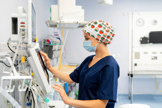 Nurse operating medical ventilator in operating room