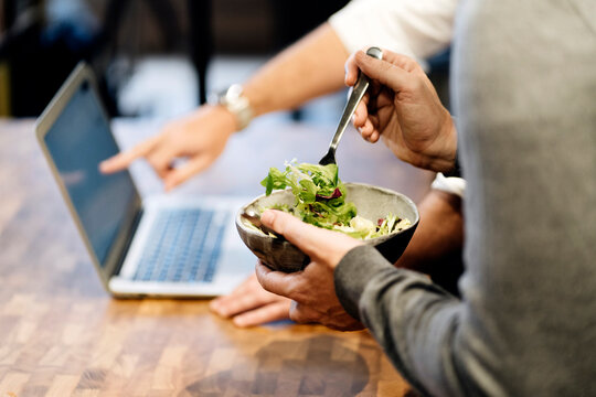 People collaborating during working lunch eating salad