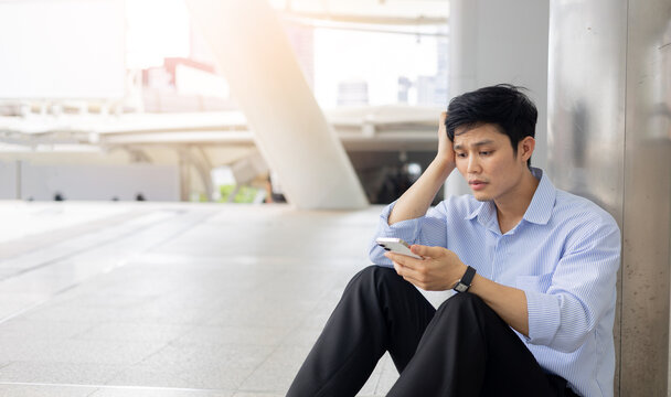 asian adult employee man sit on ground outside office with stress emotion after disappoint from job interview or unemployed for economic global and business concept