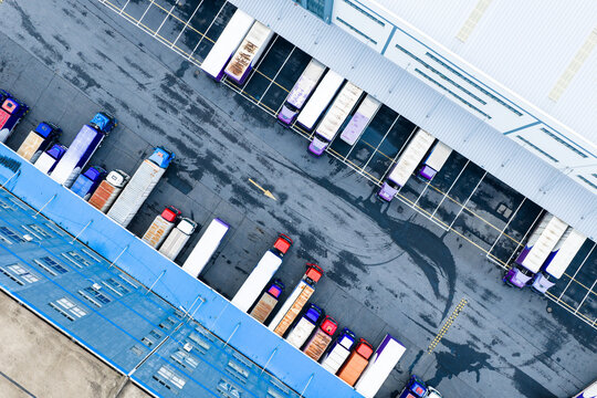 Aerial top view of logistics warehouse with solar rooftops and trucks