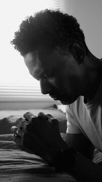 African American man kneeling beside bed in deep prayer seeking spiritual guidance
