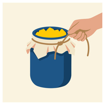 Hand tying a string around a blue jar of yellow food, preparing