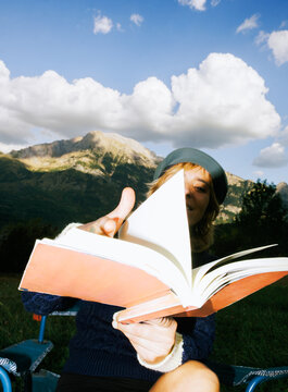 Woman reads a book in the mountains during the day