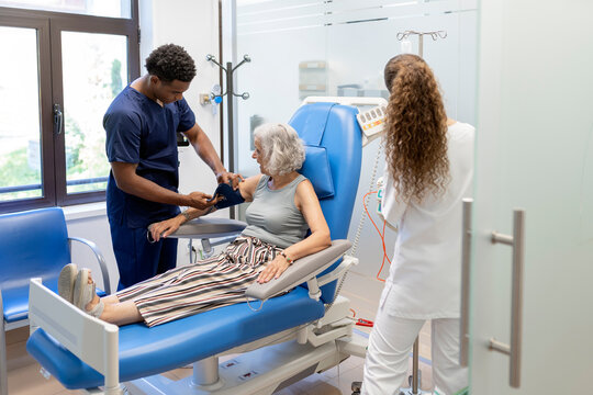 Male nurse checking blood pressure of senior patient