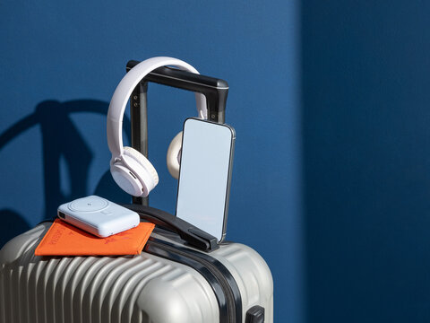 Travel Essentials On Suitcase over dark blue background